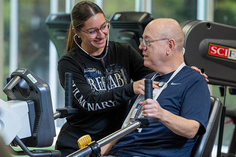 Rehab specialist monitoring a patient on a stationary bike during an outpatient therapy session.