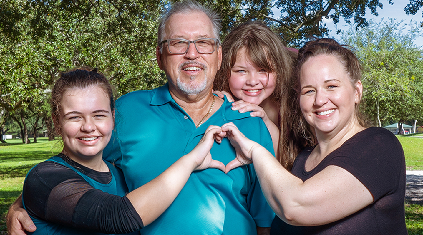family multigenerational smiling with heart hands