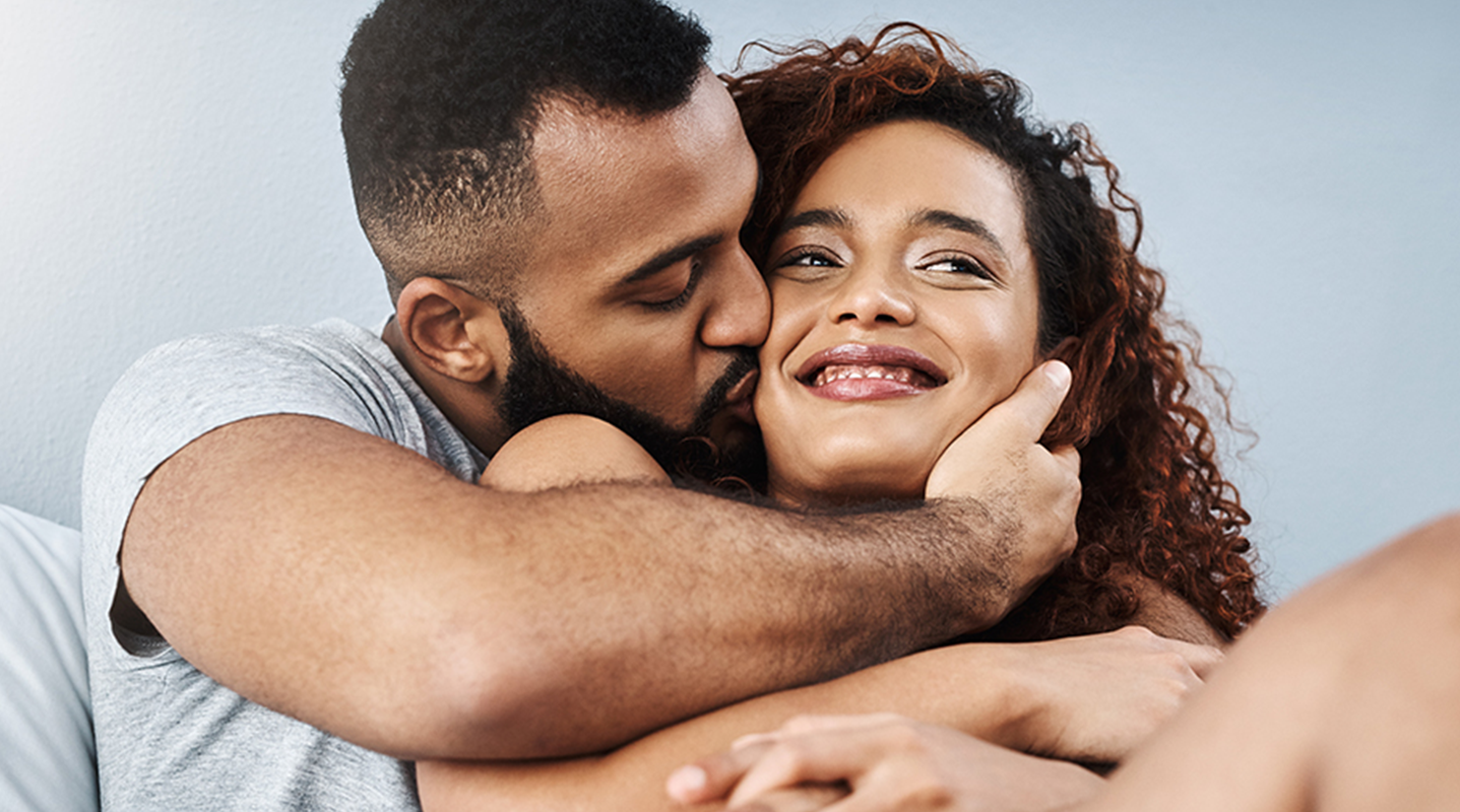 man kissing cheek of smiling woman