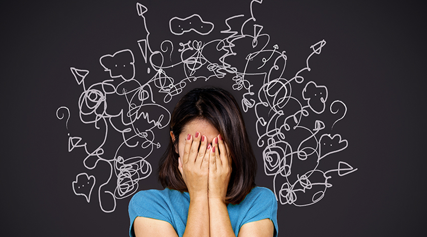 woman covering with hands face in front of chalkboard with squiggle lines