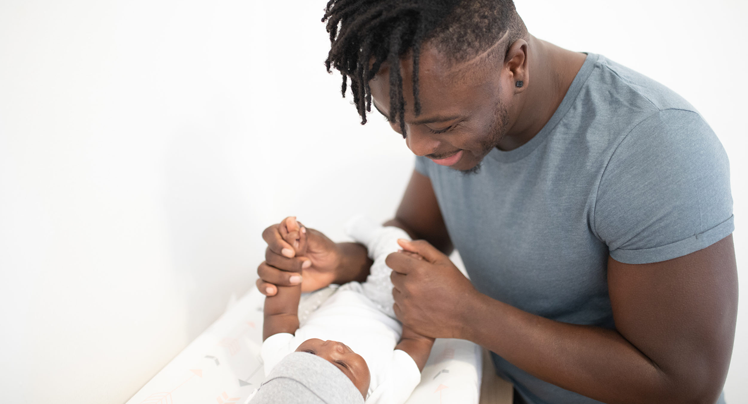 father smiling at newborn