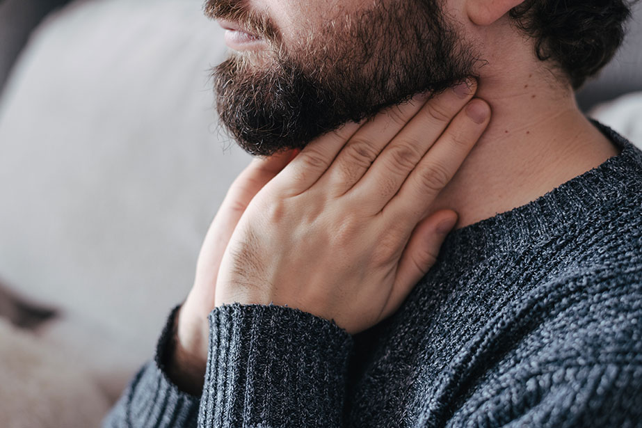 A man holding his throat because he is having trouble swallowing