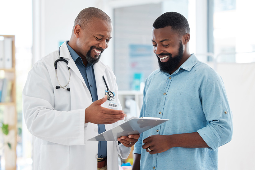 Doctor and man discuss health information while looking at clipboard